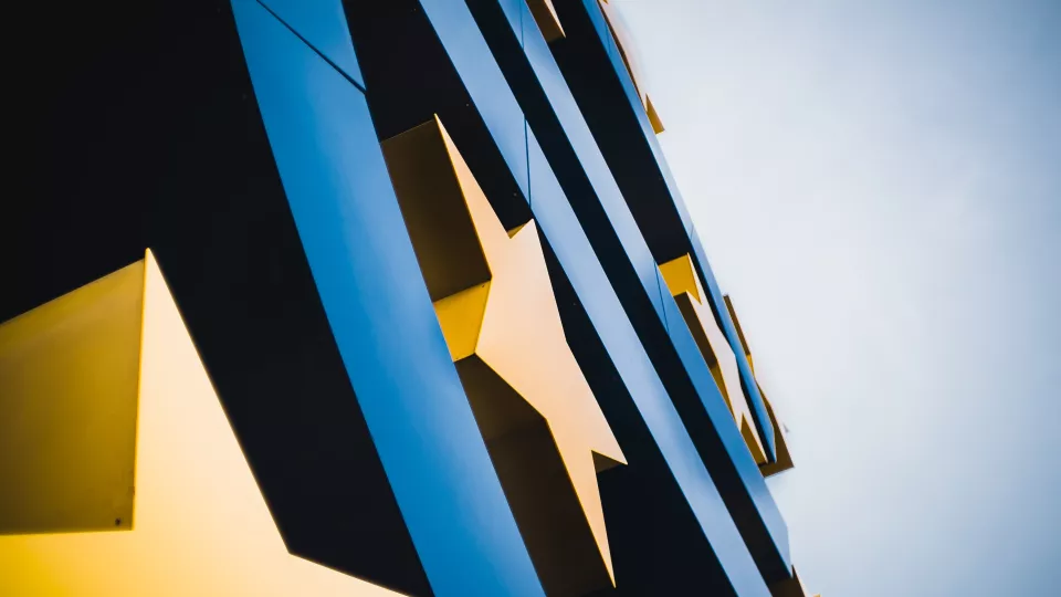 Yellow stars on a blue building. Photo Photo by Mika Baumeister on Unsplash.